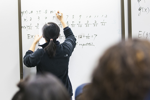faculty member writing equations on whiteboard