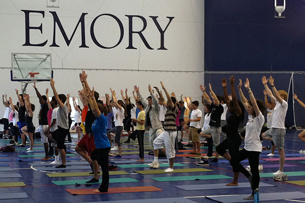 dozens of students in a gym doing a yoga pose